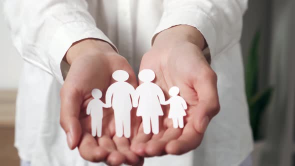 Closeup Female Hands Holding A Family Illustrated In Paper Silhouette. Family Silhouette Of People alt