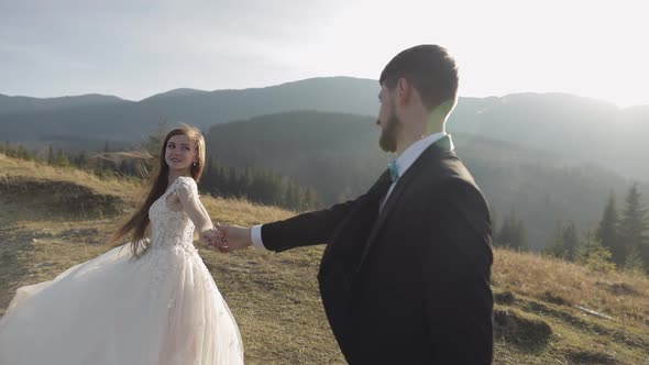 Newlyweds. Caucasian Groom with Bride Walking on Mountain Slope. Wedding Couple alt