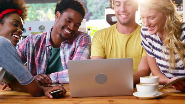 Group of friends using laptop while having cup of coffee alt