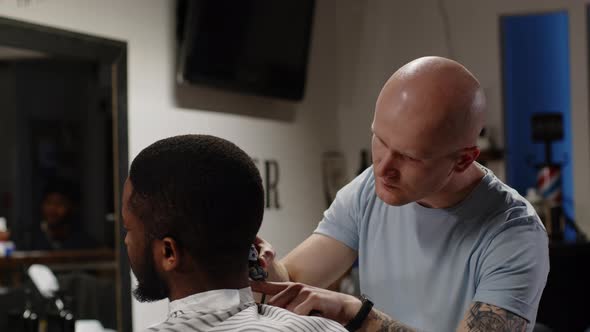 White Hair Stylist Doing Hairstyle to Handsome Young African American Man alt
