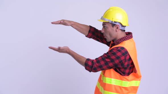Young Happy Hispanic Man Construction Worker Snapping Fingers and Looking Surprised