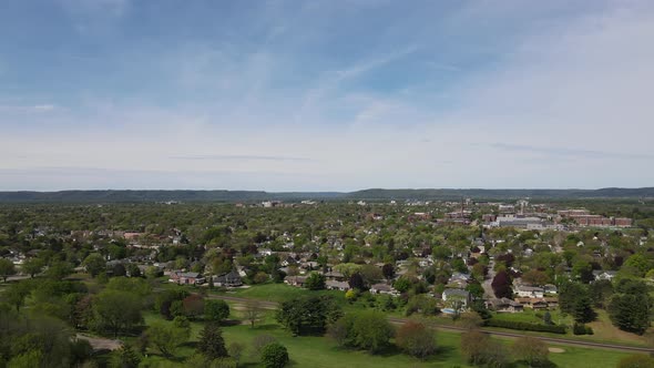 Panoramic view of city in valley in Wisconsin, brilliant blue sky, wispy clouds, mountains, forest.