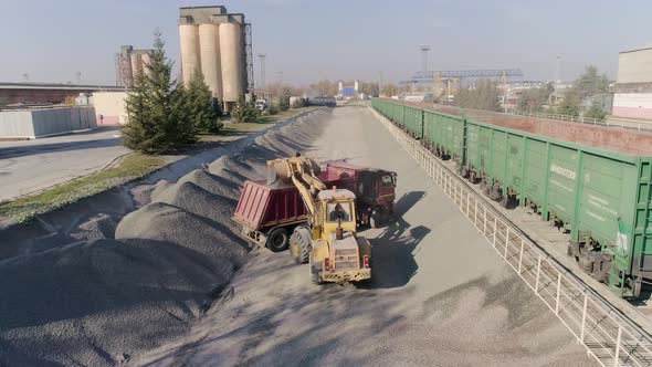Front Loader Loads Gravel Into Dump Truck Body at Construction Logistics Hub alt