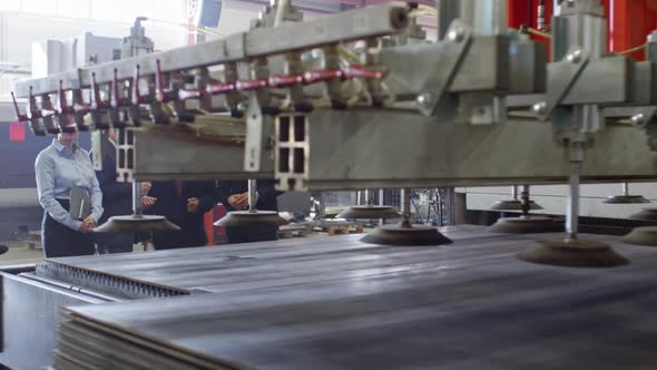 Professional Engineers Looking at Working Industrial Machine alt