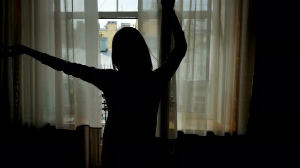 Young Woman Opening Curtains On Window At Morning And Go Out To Balcony. 