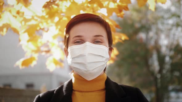 Portrait of a Beautiful Young Woman Wearing Protective Medical Mask and Standing on the Street alt