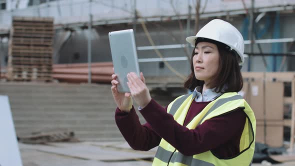 Construction worker taking picture with digital tablet of project development