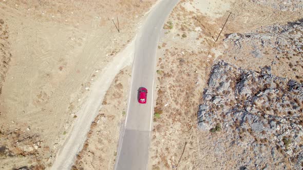 Cinematic road landscape. Yellow sand and rocks, moving car. Aerial drone flight top down shot. alt