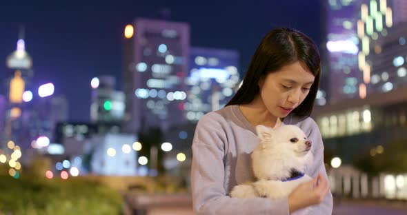 Woman playing with her dog in city at night alt
