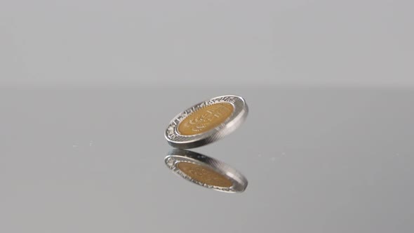 New Israeli Shekels coins falling in slow motion on a reflective surface