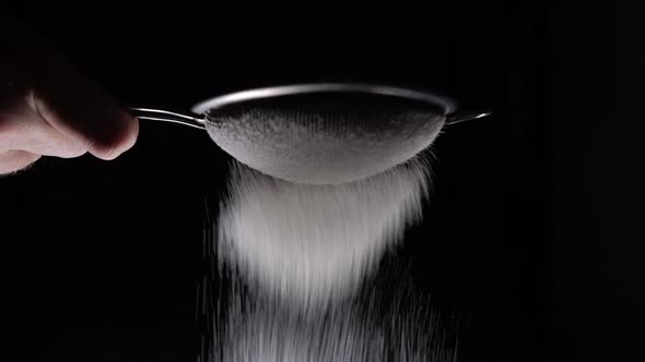 Chef Sifting Flour Through A Sieve To Prepare A Delicious Dessert On A Black Background