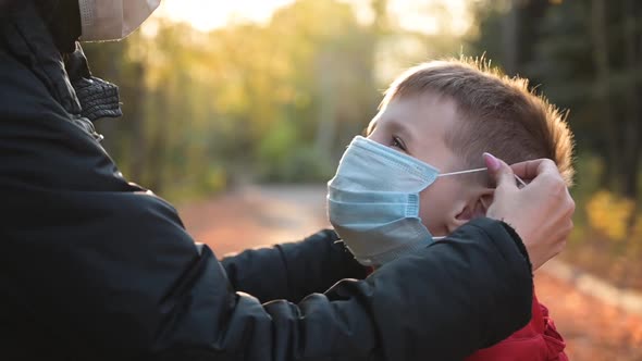 Woman Put Medical Mask on Face of Little Cute Boy and Hugs Him