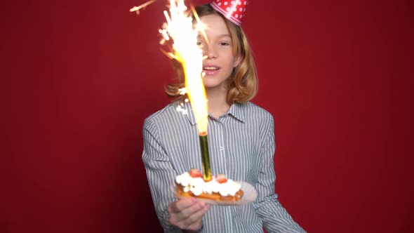 Young Teen Girl in Birthday Cap Holding Cake with Candle