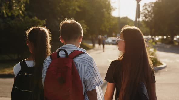 Rear View of a Shoolchildren Walk Down the Street alt
