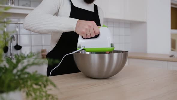 A Chef Beats Eggs with a Mixer in a Modern Kitchen alt