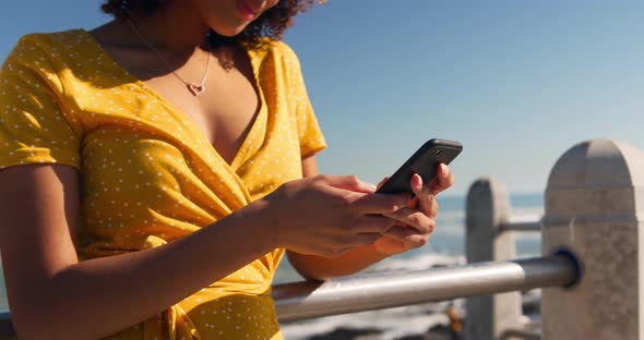 Woman using phone at beach alt