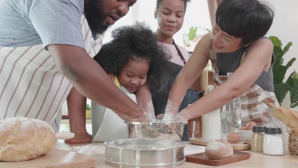 Funny together African American family helping thresh flour for pancakes in the kitchen at home