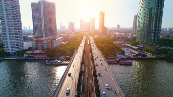 Aerial view flight over a moving sky train on a bridge over the Chao Phraya River alt