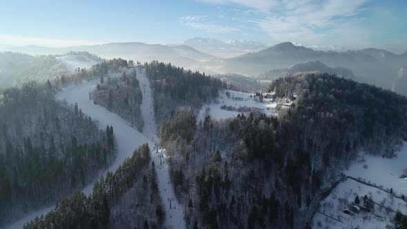 Aerial view of winter mountain resort and skiers skiing down the ski slope. Epic winter scenery