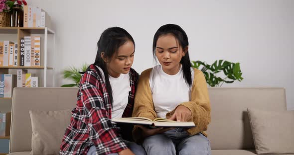 Twin girls reading book together alt