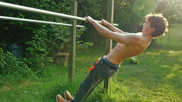 Fit young man topless doing pull up exercise on parallel bars with retracted scapula shoulder blades alt