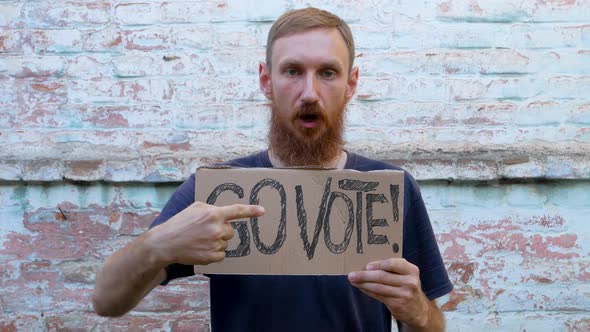 Man shows cardboard with Go Vote sign on brick wall urban background Voting concept Use your voice