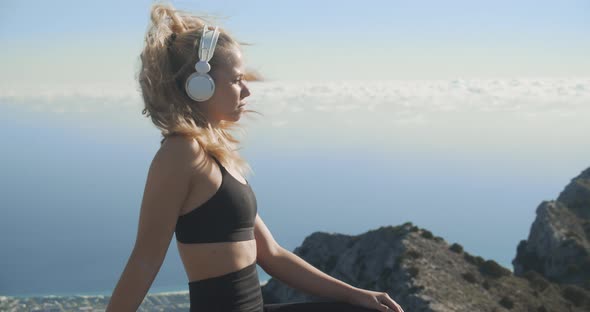 Young Woman Listening To Headphones On Mountaintop alt