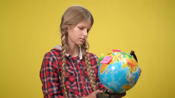 Portrait of Serious Adolescent Caucasian Girl at Yellow Background with Globe and Adhesive Stickers alt