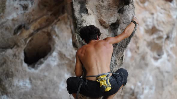 4K Young Asian man climbing on rocky mountain at tropical island on summer vacation.
