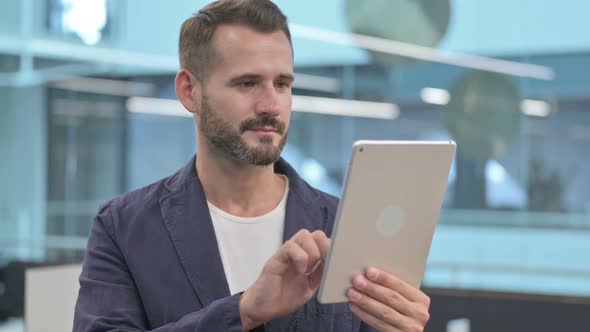 Middle Aged Businessman Celebrating on Tablet in Office alt