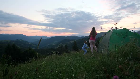 Girls Tourists are Photographed at Sunset in the Mountains They are Resting in a Green Tent alt