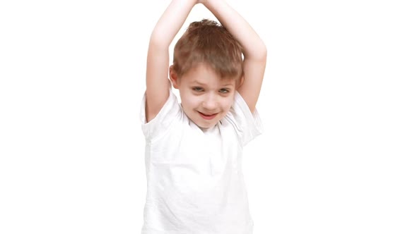 Very Young Cute Caucasian Boy Standing on White Background and Happily Raising Hands Up in Joy in alt