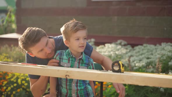Male Carpenter with His Son Working Outside Near the House alt