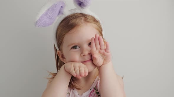 Portrain of a Funny little girl with bunny ears looking at camera