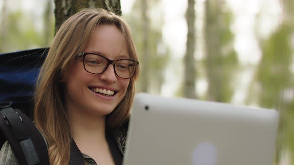 Young Caucasian Woman Traveler Having a Video Call on Her Laptop While Resting in the Forest. Close alt