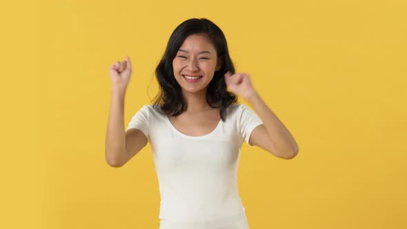 Asian woman acting excited celebrating winning and success with fist pumps