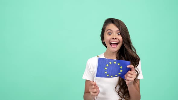 Surprised Child Waving European Union Flag on Blue Background Showing Thumb Up Schengen Visa alt