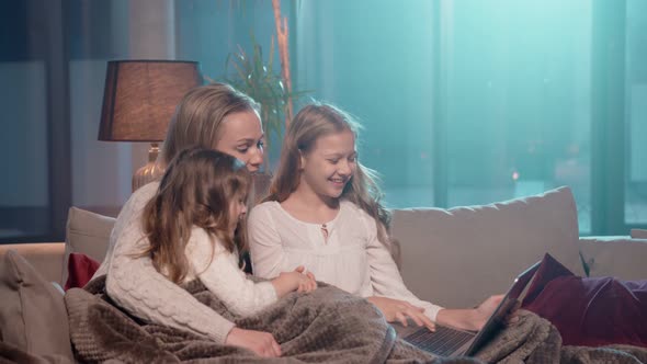Mother with Daughters Using Laptop for Video Call at Home alt