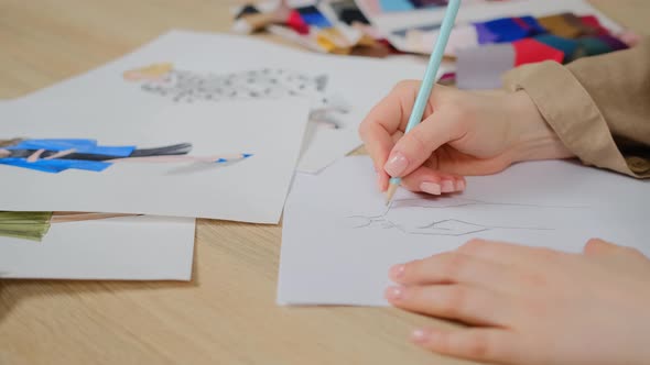 Close up of female designer using pencil and sheet of paper for fashion sketches alt