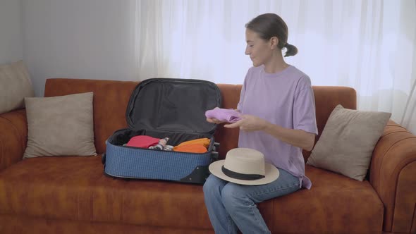 Woman Pack Clothes in a Suitcase Sitting on the Couch  Preparing for the Trip