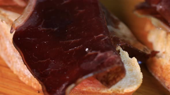 Spanish traditional pincho of beef ham on bread. Rotation motion, close up view macro shot. alt