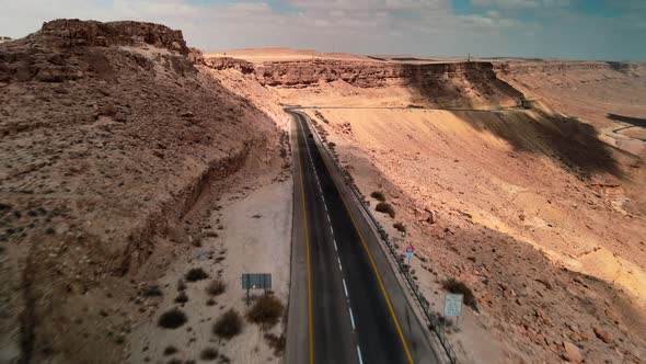 Car Driving on Asphalt Road Through the Desert Sands of the Blue Sky White Clouds