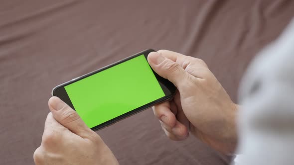 Surfing on  Internet with  greenscreen smart phone  in man hands 4K 2160p 30fps UltraHD footage - In alt