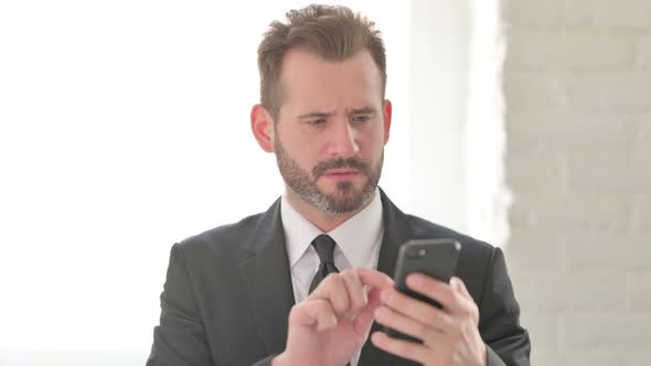 Young Businessman Reacting to Loss on Smartphone alt