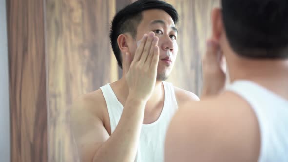 Young Asian Man Applying Skincare Cream in Bathroom alt
