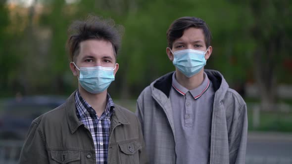 Two Friends Wearing Medical Masks Looking at the Camera Near the Road