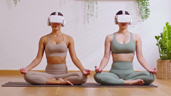 Couple Asian young woman sit on yoga mat wear virtual reality glasses doing breathing exercise yoga alt