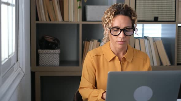 Serious businesswoman sitting in office using laptop