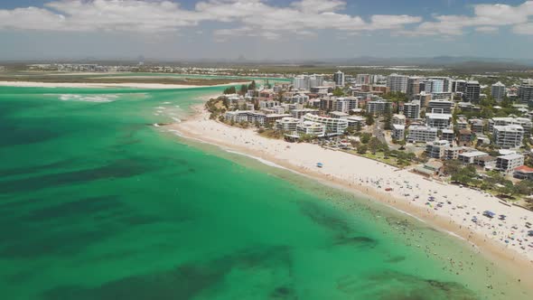 Aerial drone footage of ocean waves on a busy Kings beach, Caloundra, Australia alt