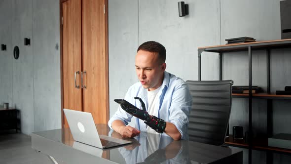 Serious man programmer with bio hand prothesis talks on smartphone alt